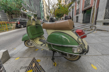 Fototapeta na wymiar Green and tan vintage moped on street in urban Madrid