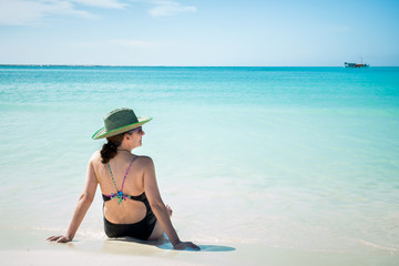 Woman with a sun hat sitting on the beach. La Tortuga Island, Venezuela
