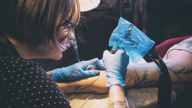 Tattoo artist make tattoo in studio, tattooing on the body. Floral tattoo