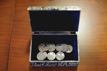Monedas de plata arras de boda en pequeño baúl plateado con interior de terciopelo negro