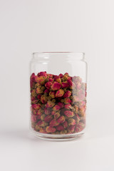 tea rose buds in the transparent jar isolated on white background
