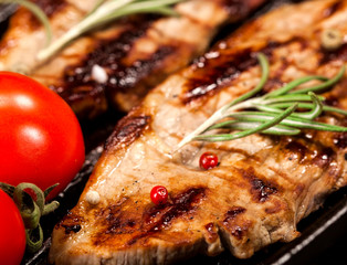 Grilled beef steak with vegetables and spices on black background