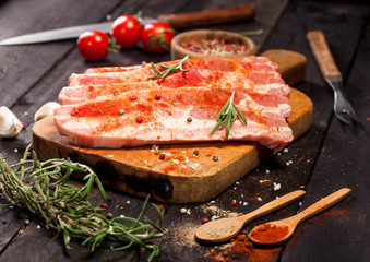 Raw pork steak on a cutting board with spices.