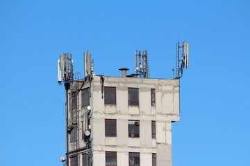 Cell phone antennas and transmitters on top of old dilapidated industrial building with metal steps...