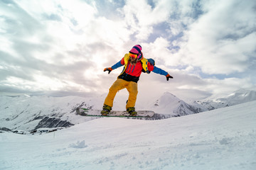 Naklejka na ściany i meble Snowboarder at jump inhigh mountains at sunny day.