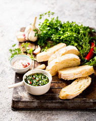  Argentinian green Chimichurri with ingredients.Raw homemade with ciabatta.Salsa or sauce made of parsley, garlic, oregano, hot pepper, olive oil, vinegar.Food Concept.