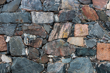 Stone wall texture. Masonry with natural cobblestones and granite slabs