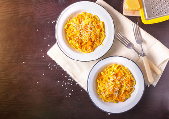 Pumpkin tagliatelle pasta with pumpkin cream parmesan cheese in white plate on dark background