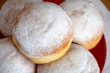 Doughnuts powdered with white ground sugar on a plate. Tasty homemade food close up view