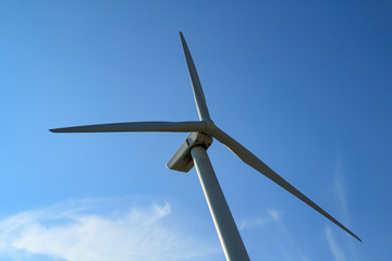 power generating wind turbine against a clear blue sky