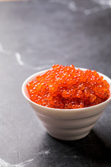 Salmon  Red Caviar in a white plate on a dark background. Healthy Food Concept. Snack.Copy space for Text.Seafood.