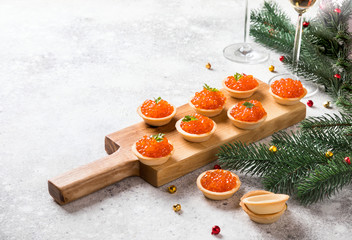 Christmas and New Year holidays composition. Red Salmon Caviar in wooden bowl, Tartlets Festive...