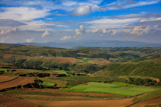 Country Scenery in Dashanbao - National Nature Reserve. Zhaotong, Zhaoyang District, Yunnan Province, China. Blue Sky, Orange Soil, Green Fields of Grass, Beautiful Chinese Farmland Landscape