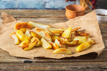 Crisp golden deep fried, french fries hot potatoes, frying and ready to be eaten, really yummy.Potatoes on craft paper on a rustic wooden background