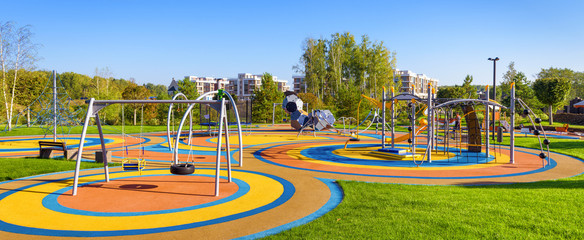 Panorama of colorful large playground in city park. Empty modern outdoor playground in summer....