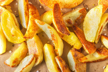 Crisp golden deep fried, french fries hot potatoes, frying and ready to be eaten, really yummy.Potatoes on craft paper on a rustic wooden background