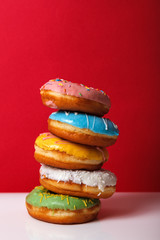 Donuts in multi-colored glaze stacked on top of each other on a red background, copy space. Bakery advertising concept