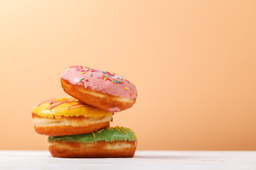 Three multi-colored donuts on a beige background. Copy space. Concept of feeding sweets to the bakery. Hanukkah