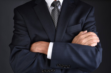 Closeup of a man in a gray business suit with his arms crossed