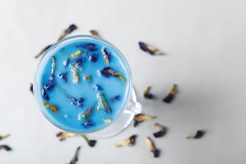 Pour the milk into a Cup of blue butterfly pea tea Anchan on a gray background. Blue Thai tea and...