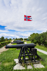 Row of cannons and Norwegian flag in front of Kristiansten Fortress, Trondheim, Norway