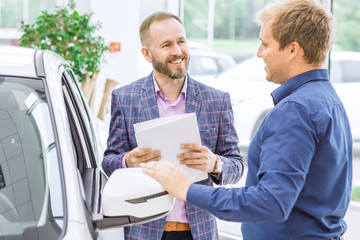 Salesman and his client at the car dealership