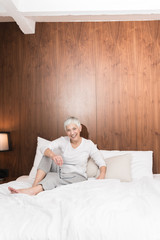 Senior cheerful woman sitting on a bed