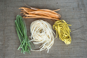 Colorful raw italian pasta on a jute fabric