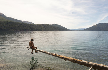 Meditating sitting on a tree above the lake.