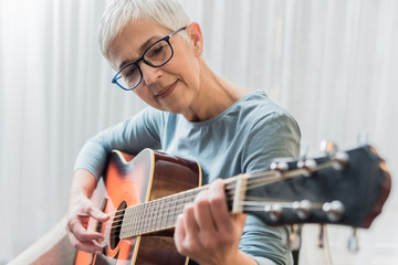 Woman practicing to play guitar - Powered by Adobe