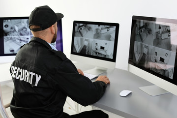 Male security guard monitoring home cameras indoors