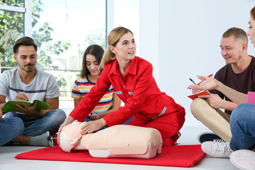 Instructor demonstrating CPR on mannequin at first aid class indoors