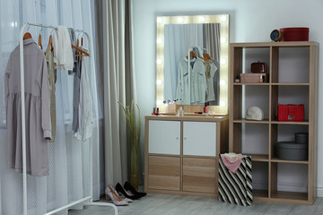Fototapeta na wymiar Dressing room interior with makeup mirror, wardrobe rack and shelving unit