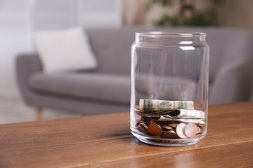 Donation jar with money on table against blurred background. Space for text