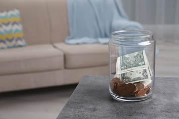 Donation jar with money on table against blurred background. Space for text