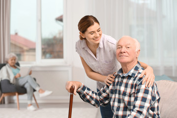 Elderly man with female caregiver at home. Space for text