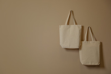 Eco tote bags hanging on color wall. Space for design