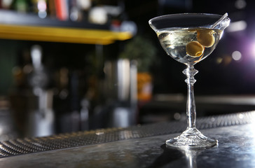 Glass of martini cocktail with olives on bar counter. Space for text