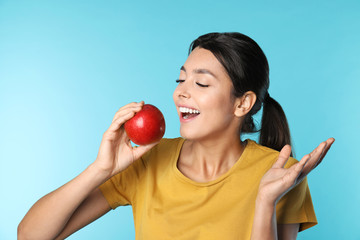 Young woman with healthy teeth and apple on color background