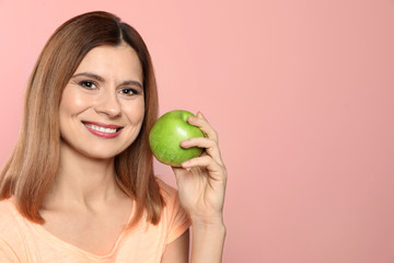 Smiling woman with perfect teeth and green apple on color background. Space for text