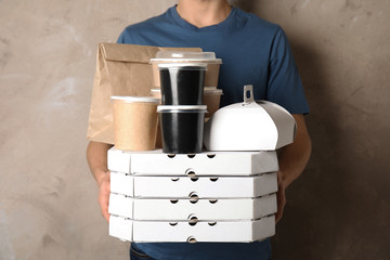 Fototapeta na wymiar Courier with stack of orders on beige background. Food delivery service