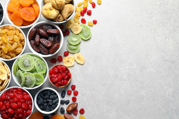 Bowls of different dried fruits on grey background, top view with space for text. Healthy food