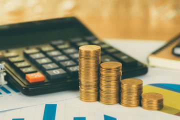 Coin stack and financial graph paper sheet with calculator on working table, business planning vision and finance analysis concept.