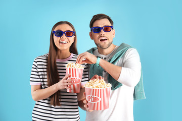 Obraz premium Couple with 3D glasses and tasty popcorn on color background