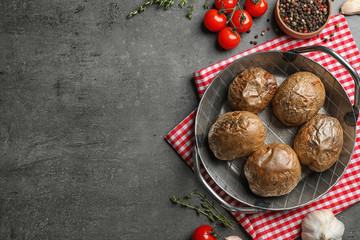 Frying pan with tasty baked jacket potatoes on grey background, top view. Space for text