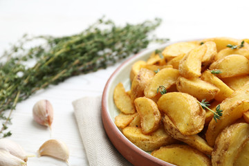 Plate with tasty baked potato wedges on wooden table, closeup. Space for text
