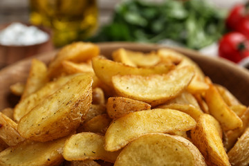 Bowl with tasty baked potato wedges, closeup