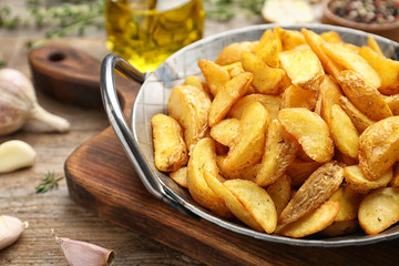 Frying pan with tasty baked potato wedges on wooden table, closeup. Space for text