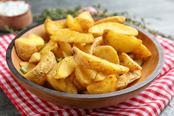 Plate with tasty baked potato wedges on table
