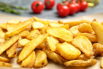 Delicious baked potato wedges on parchment paper, closeup